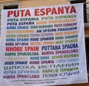 Pancarta amb missatges controvertits sobre Espanya en diversos idiomes.